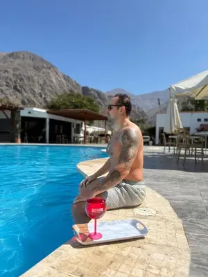 a man sitting on the edge of a swimming pool at Regina Hotel in Lunahuaná