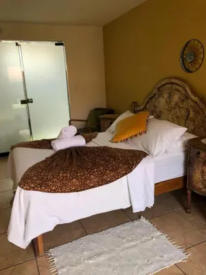 a bedroom with a bed with white sheets and orange pillows at Hostal Sol Y Luna - Cieneguilla in Cieneguilla