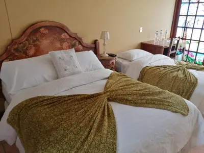 a bedroom with two beds with white sheets at Hostal Sol Y Luna - Cieneguilla in Cieneguilla