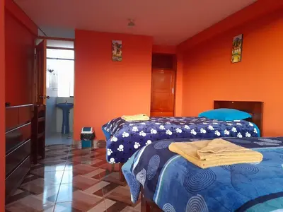 two beds in a room with orange walls at Hospedaje Encanto de Chinchero in Chinchero