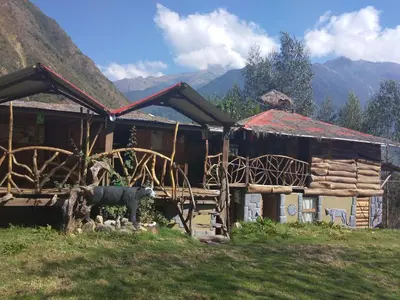 a log cabin with a cow standing in front of it at Albergue Salkantay Chawllay in Santa Teresa