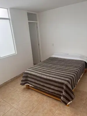a bed in a white room with a striped blanket at Apartamento 302 cerca a la playa in Punta Negra