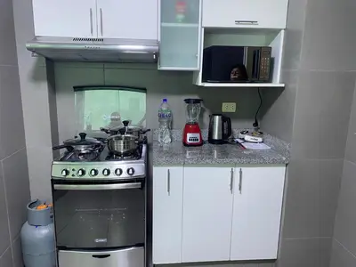 a kitchen with a stove and white cabinets and a person at Hermoso apartamento de 3 habitaciones frente a parque en San Isidro in Lima