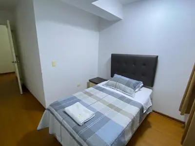 a small bedroom with a bed with a blue and gray bedspread at Hermoso apartamento de 3 habitaciones frente a parque en San Isidro in Lima