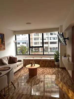 a living room with a couch and a large window at Acogedor departamento en Malecón Balta con Piscina in Lima