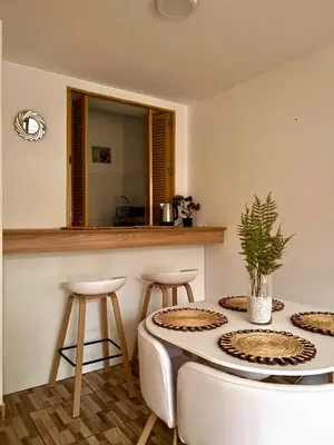 a kitchen with a table and two stools and a mirror at Acogedor departamento en Malecón Balta con Piscina in Lima