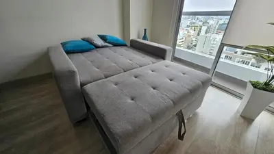 a couch in a living room with a large window at Nordic Barranco by PERU STAY in Lima