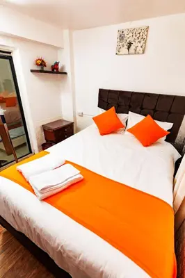 a bedroom with a large bed with orange pillows at Mayu House Inn II a minutos del centro histórico in Cusco