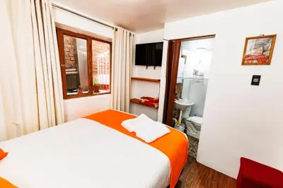 a bedroom with a white bed and a window at Mayu House Inn II a minutos del centro histórico in Cusco