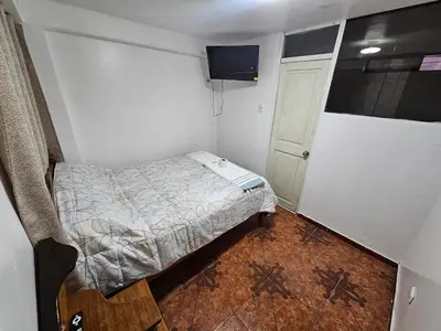 a small bedroom with a bed and a small window at Pantaq hostal in Cusco