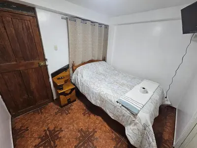 a small bedroom with a bed and a wooden door at Pantaq hostal in Cusco
