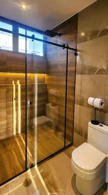 a bathroom with a toilet and a glass shower at Private 4BR Getaway with Pool & Cinema in Ica
