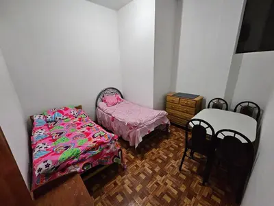 a bedroom with two beds and a table and chairs at Munay Ayllu- Tu refugio familiar en Huánuco in Huánuco