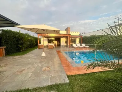a house with a swimming pool and an umbrella at Condominio ecológico las gardenias de Asia in Asia