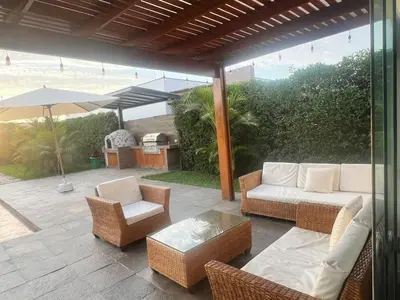 a patio with a couch and chairs and an umbrella at Condominio ecológico las gardenias de Asia in Asia