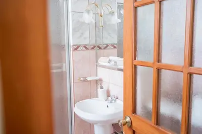 a bathroom with a sink and a glass shower at Moty's Guesthouse in Cusco