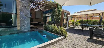 a swimming pool in front of a house with an umbrella at Quiet 2BR Villa whit Pool & Games in Ica