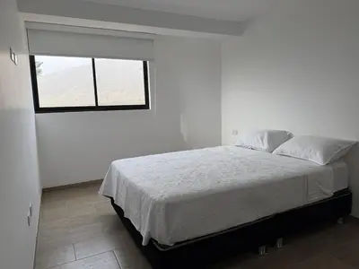 a white bedroom with a bed and a window at Casa de Playa de Estreno in San Antonio