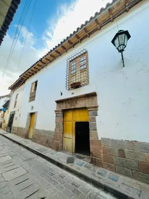 a white building with a door and a lamp at Acogedor Departamento Vitoque in Cusco