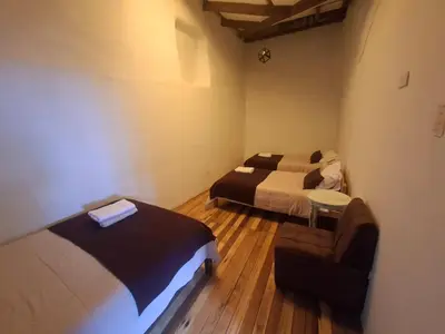 a room with two beds and a chair in it at Acogedor Departamento Vitoque in Cusco