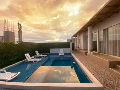 a swimming pool with two chairs and a building at Casa de Playa - Mara House in Huacho