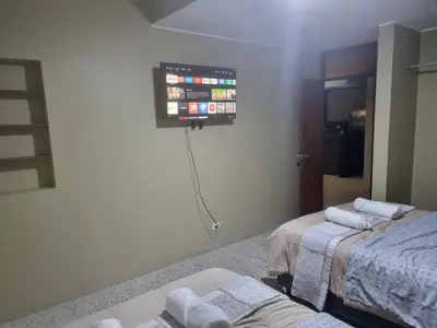 a room with two beds and a tv on the wall at Departamento en Ica super céntrico en Urb San Miguel in Ica