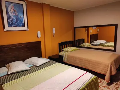a hotel room with two beds and a mirror at Rouse Hostal Confort in Huancayo