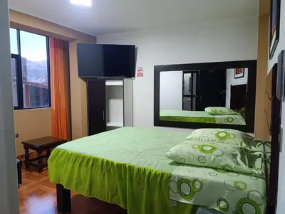 a bedroom with a green bed and a mirror at Rouse Hostal Confort in Huancayo