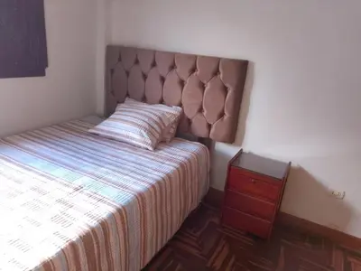 a bedroom with a bed with a headboard and a night stand at El despertar del inka in Cusco