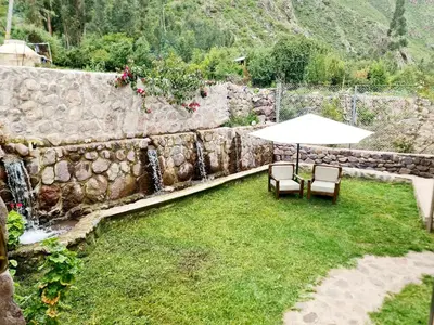 a patio with two chairs and an umbrella next to a stone wall at Beautiful house in the Sacred Valley, Arin Falls in Calca