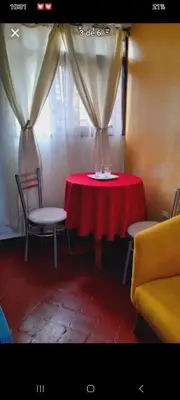 a red table with two chairs and a window at Habitación en Barranco in Lima