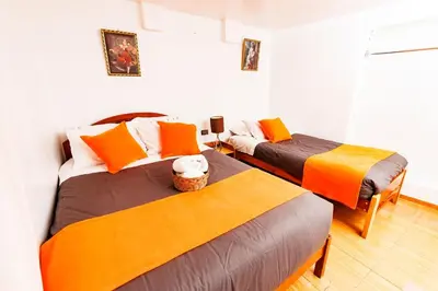two beds in a room with orange and grey at Mayu House Inn a minutos del centro histórico in Cusco