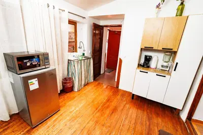 a kitchen with a refrigerator and a wooden floor at Mayu House Inn a minutos del centro histórico in Cusco