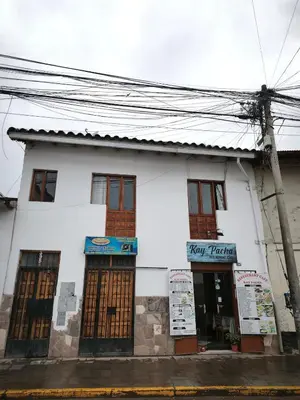 a white building with brown doors on a street at Mayu House Inn a minutos del centro histórico in Cusco