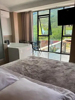 a bedroom with a bed and a tub and a large window at Hotel Roma Quillabamba in Quillabamba