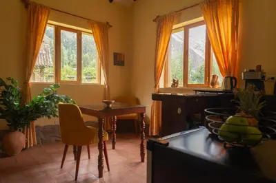 a living room with a table and chairs and windows at Cabin in Inca Sanctuary in Ollantaytambo