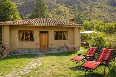 a small house with red chairs in front of it at Cabin in Inca Sanctuary in Ollantaytambo