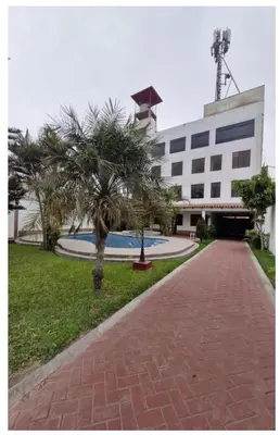 a building with palm trees in front of a sidewalk at Modern Apartament Pool & Jacuzzi 1 room in Lima