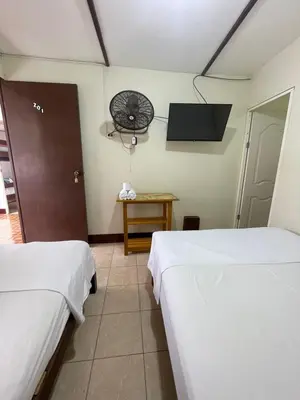 a room with two beds and a fan on the wall at HOSPEDAJE VISTA DEL SOl PARACAS in Paracas
