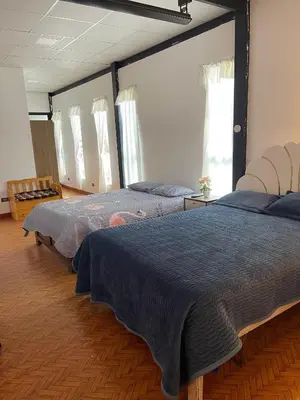 two beds in a large room with windows at Casa La Morada Ecolodge in Ayacucho