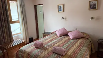 a bedroom with a bed with two pink pillows on it at Casa Elena in Cusco