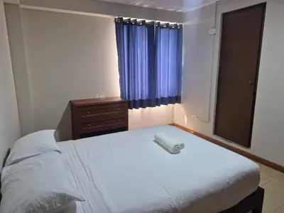 a bedroom with a white bed and a dresser and a window at Hotel Naciones Unidas in Lima