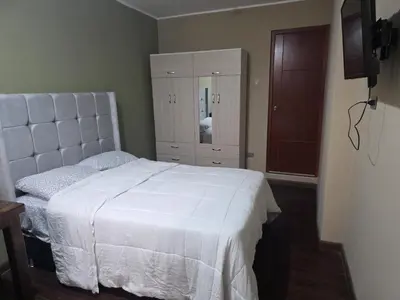 a bedroom with a white bed and a dresser at room rent in Lima