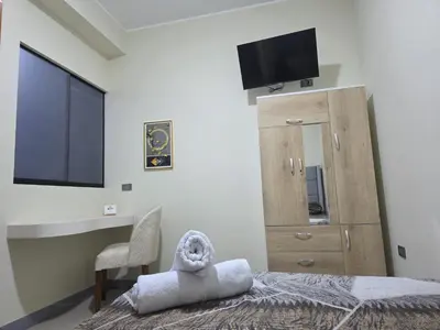 a bedroom with a bed with a television and a chair at room rent in Lima