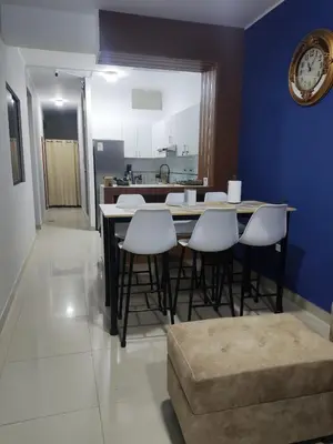 a kitchen with a table with white chairs and a clock at room rent in Lima
