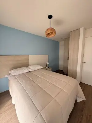 a large white bed in a bedroom with a blue wall at Departamento con vista al Mar in San Bartolo