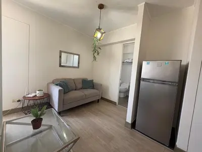 a living room with a couch and a refrigerator at Departamento en barranco in Lima