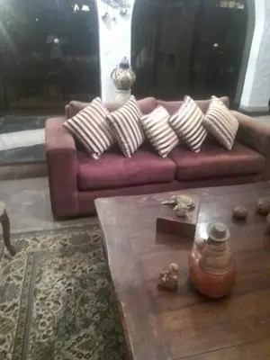 a living room with a red couch with pillows at Nice country house with a swimming pool and large garden in Cieneguilla