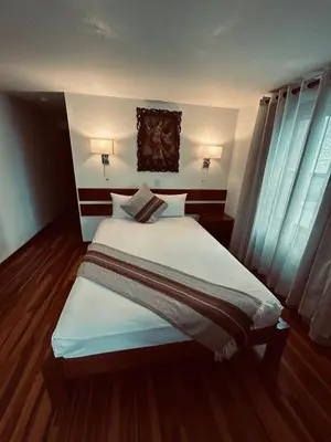 a bedroom with a large bed with white sheets at Xima Cusco Kenamari in Cusco