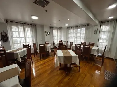a dining room with tables and chairs and windows at Xima Cusco Kenamari in Cusco